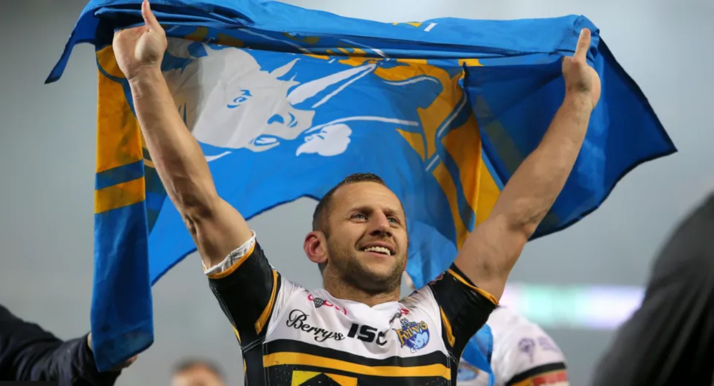 Rob Burrow triumphantly holding a Leeds Rhinos flag